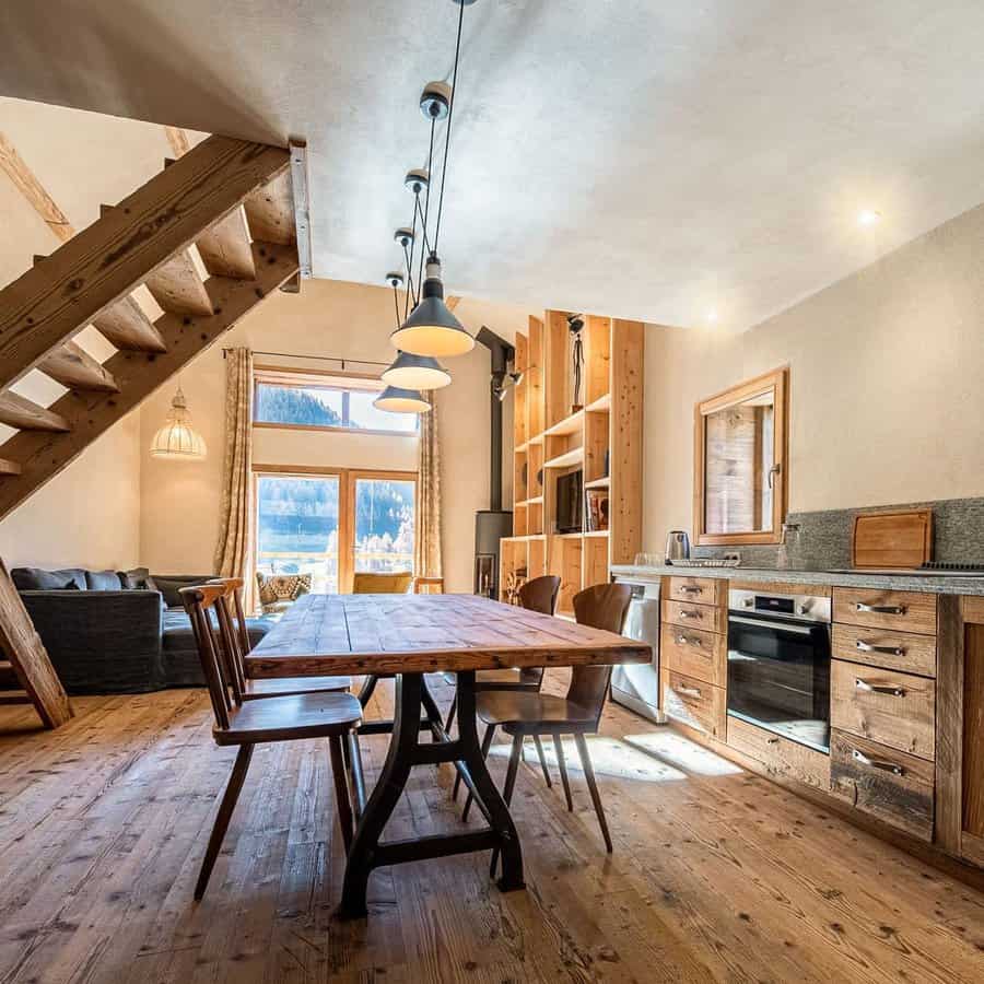 Rustic dining and kitchen area with wooden furniture, stairs, and cozy seating