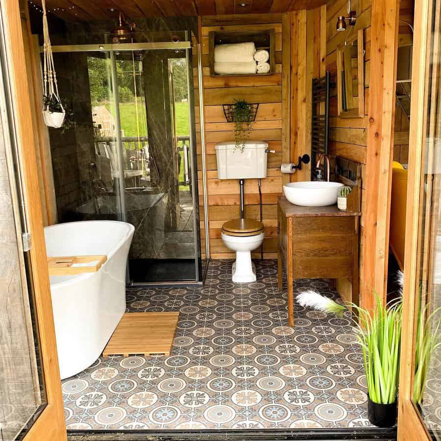 Cozy rustic bathroom with wood paneling, a freestanding tub, glass shower, and vintage-style decor for a warm cabin retreat feel