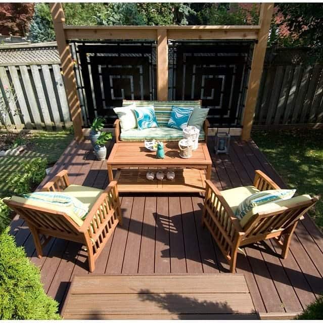 Outdoor patio with wooden furniture: two chairs, a bench with green cushions, and a coffee table