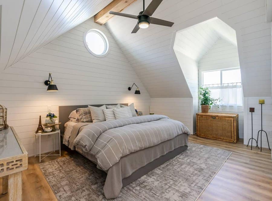 Bright attic bedroom with shiplap walls, exposed beams, and cozy neutral bedding, creating a modern farmhouse-inspired retreat.