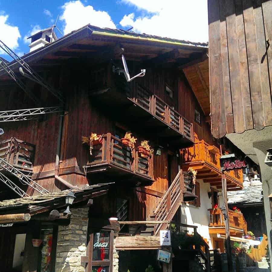 Charming wooden alpine buildings with flower boxes under a bright blue sky, captured in a picturesque mountain village