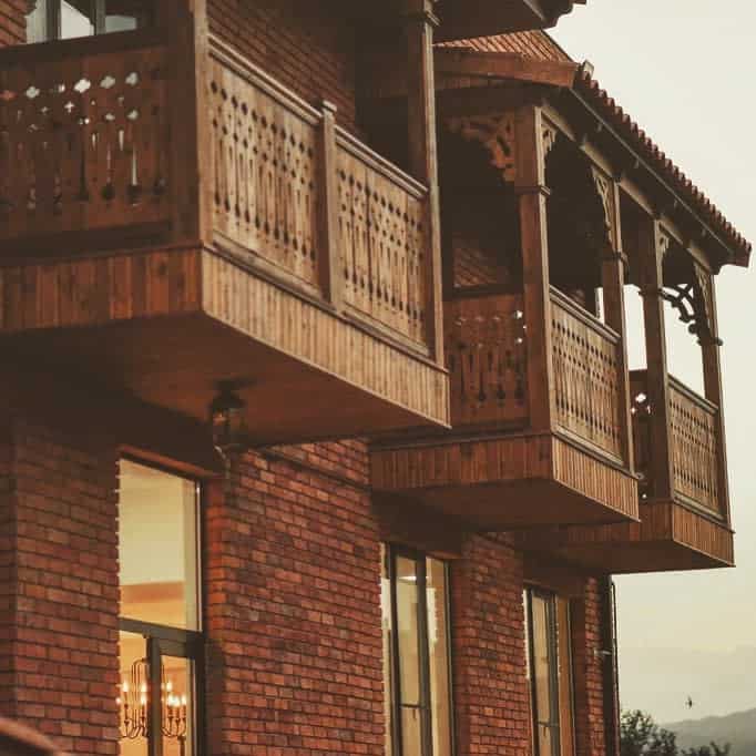 Traditional wooden balconies with intricate carvings on a brick house, adding rustic charm and elegance to the architecture