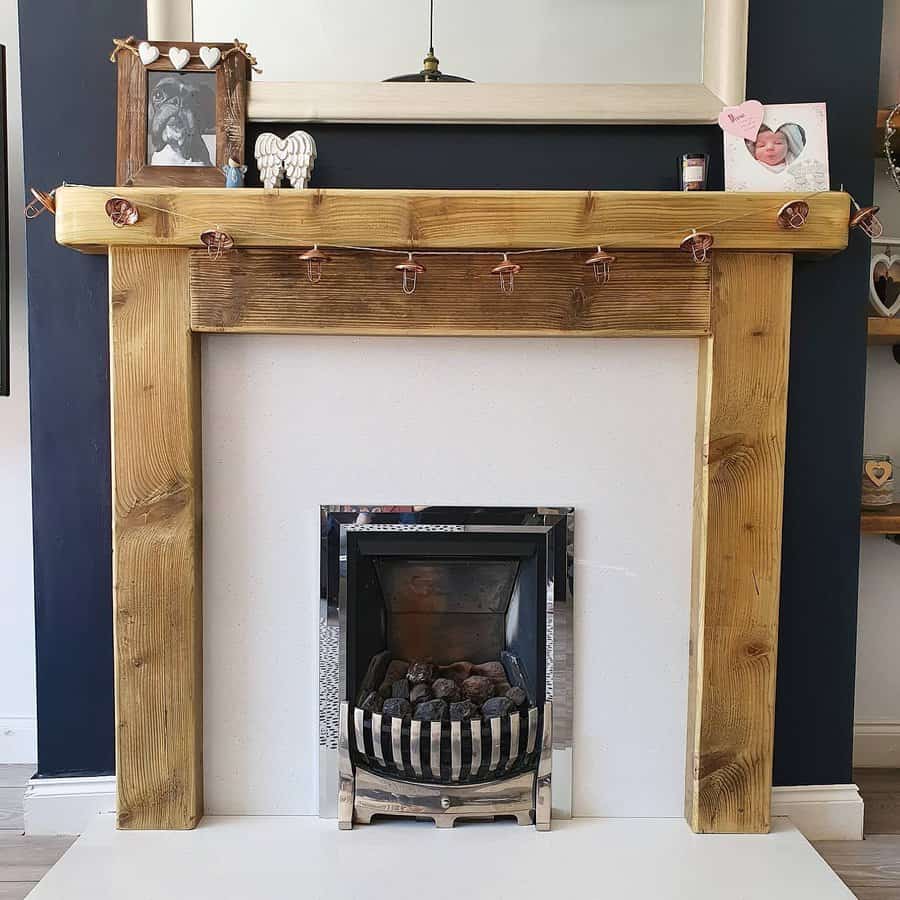 A rustic wooden fireplace mantel with a natural wood finish, decorated with a photo frame, angel figurine, and a string of heart-shaped clips, adding a cozy and personalized touch to the room