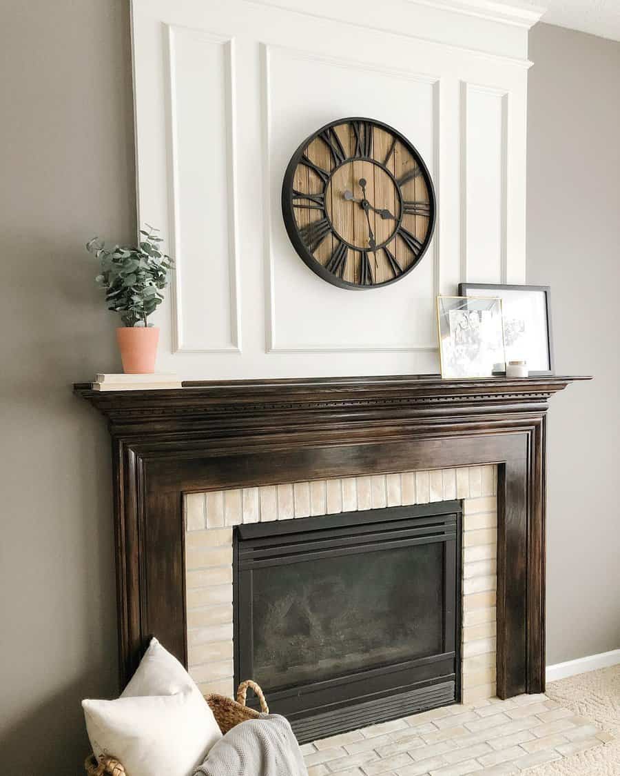 A classic wooden fireplace mantel with a brick surround, framed by a large wall clock and artwork, creating a clean and stylish focal point in the living room