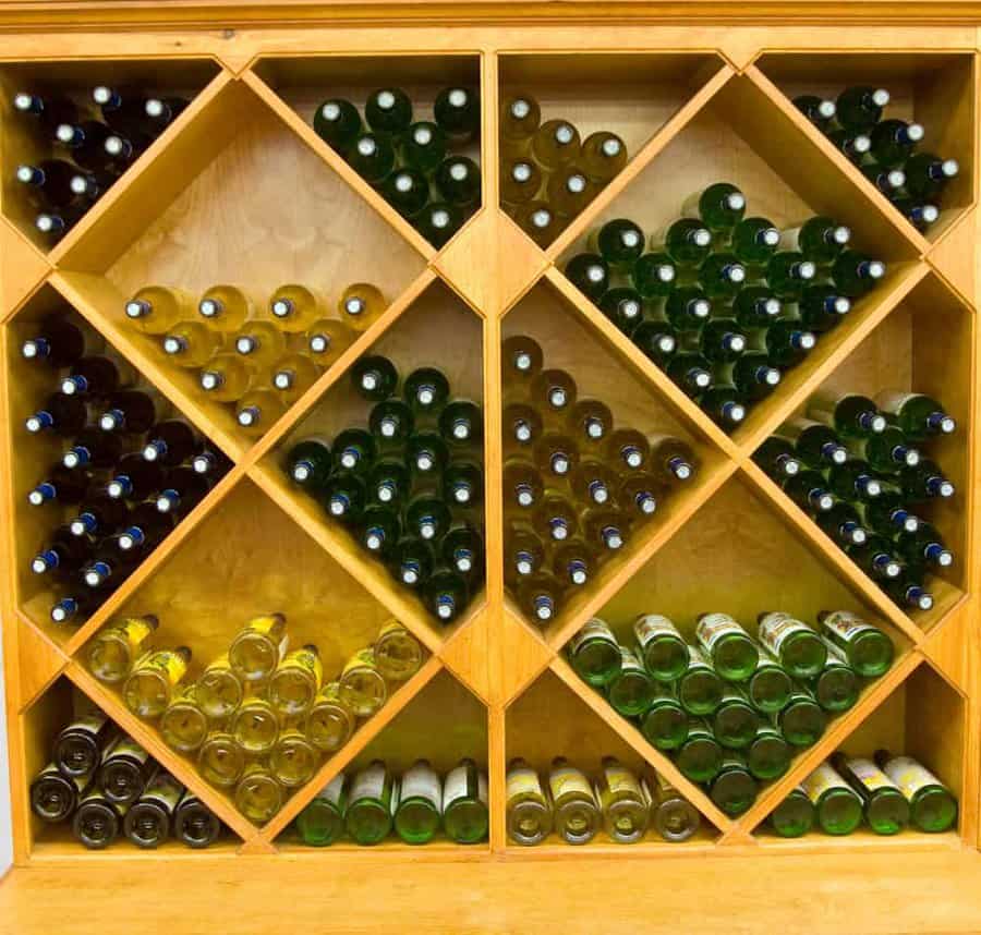 Wooden wine rack with diamond-shaped compartments, holding various bottles of wine stacked horizontally