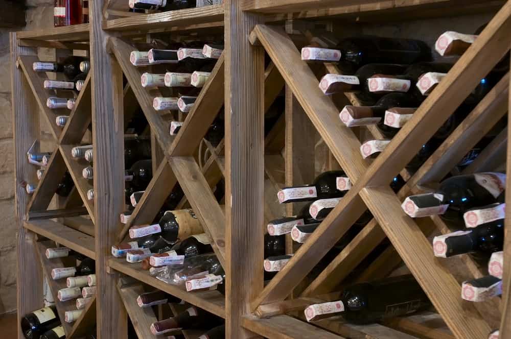 Rustic wooden wine rack with an X-shaped design, neatly storing bottles in a traditional cellar-style arrangement