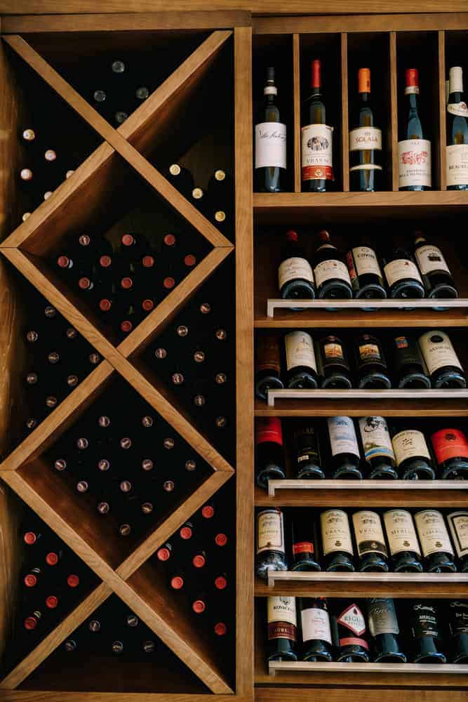 Elegant wooden wine rack featuring X-shaped compartments and vertical shelving, neatly organizing a variety of wine bottles