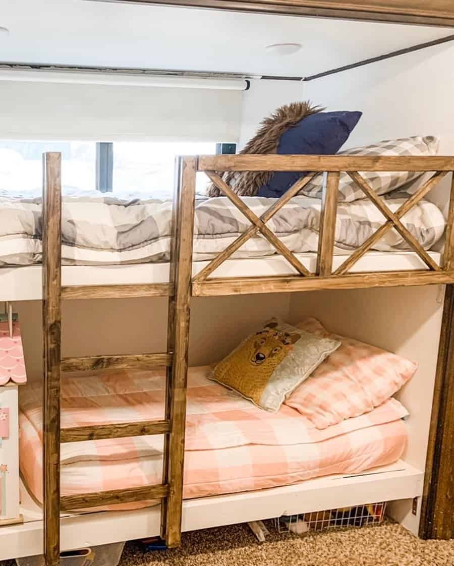 Wooden bunk beds with plaid bedding and decorative pillows, one featuring a fox design; sunlight filters through a window behind