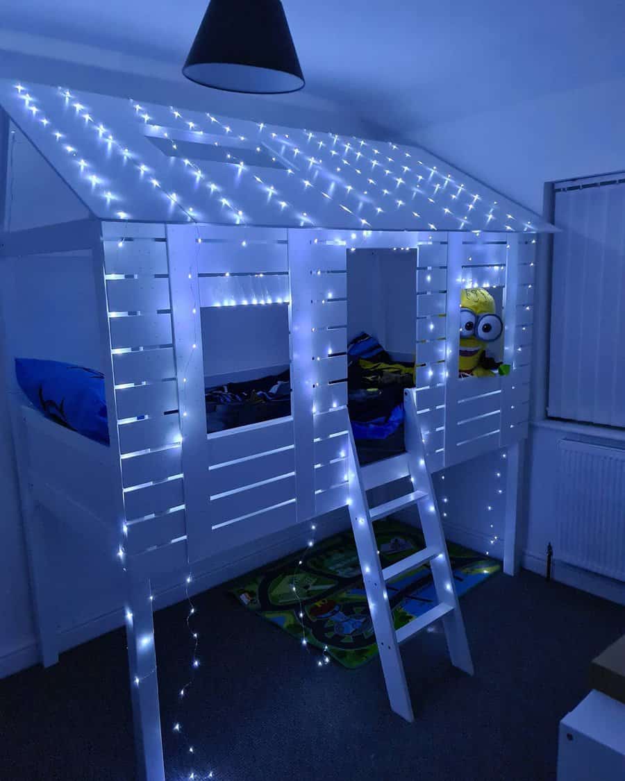 Children's loft bed shaped like a house, adorned with white string lights