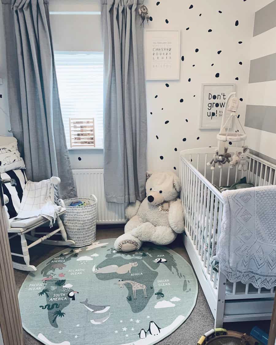 Nursery with a crib, teddy bear, rocking chair, and a round rug featuring a world map in neutral tones and playful decor accents