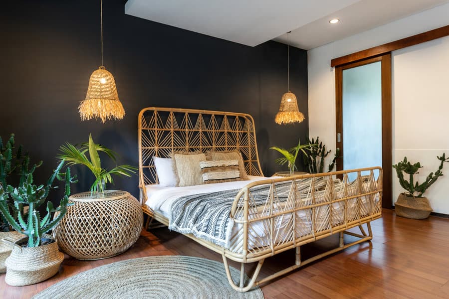 Boho bedroom with black wall and rattan furniture