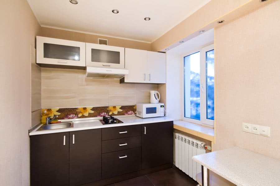 Compact kitchen with white cabinets, dark base, and floral backsplash