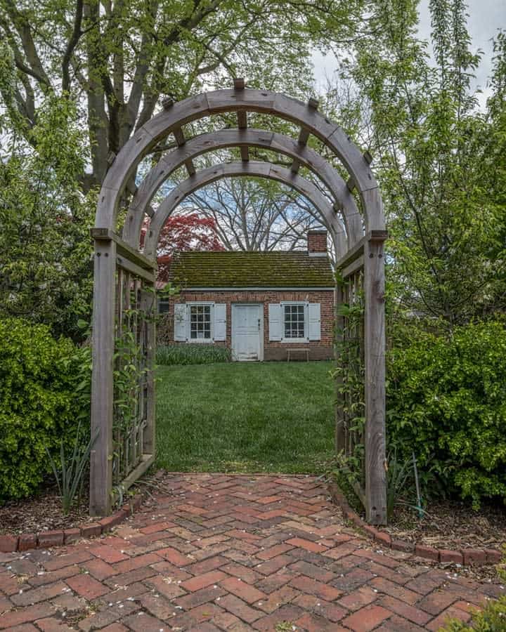 Wooden arbor over brick path leading to a house