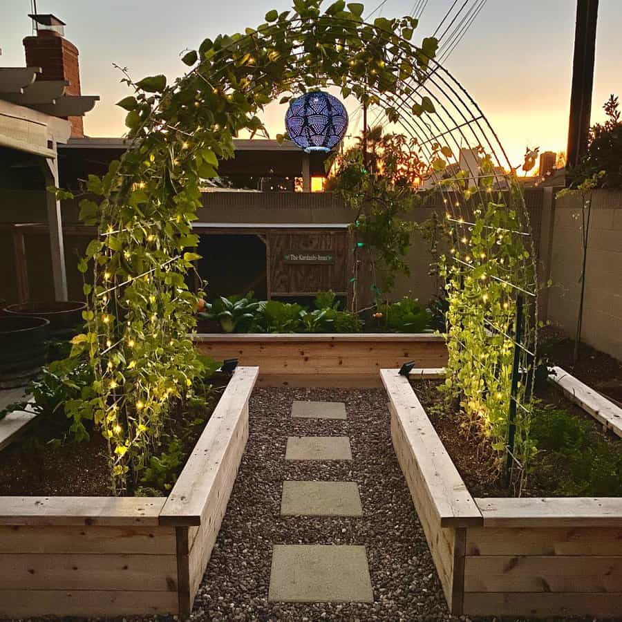 Evening view of garden arch with lights and raised beds