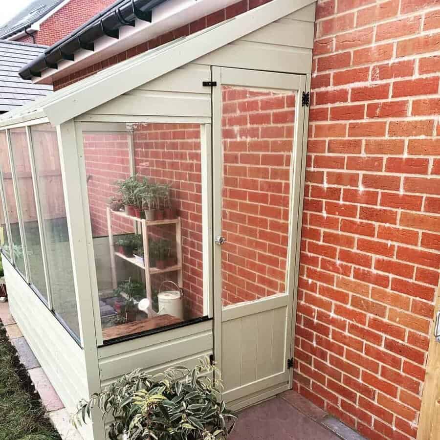 Lean to greenhouse against a red brick wall