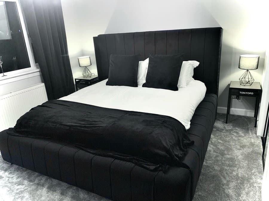 Monochrome bedroom with plush black bed and grey carpet