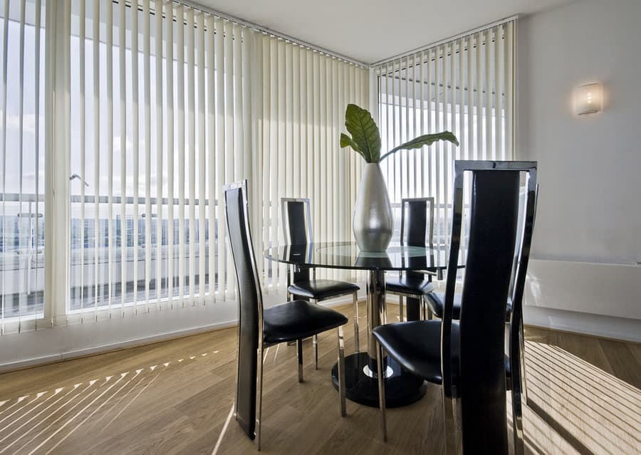 Dining room with vertical blinds and a glass table