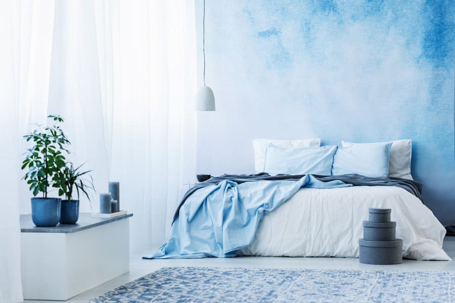 Airy bedroom with blue watercolor wall and light textiles