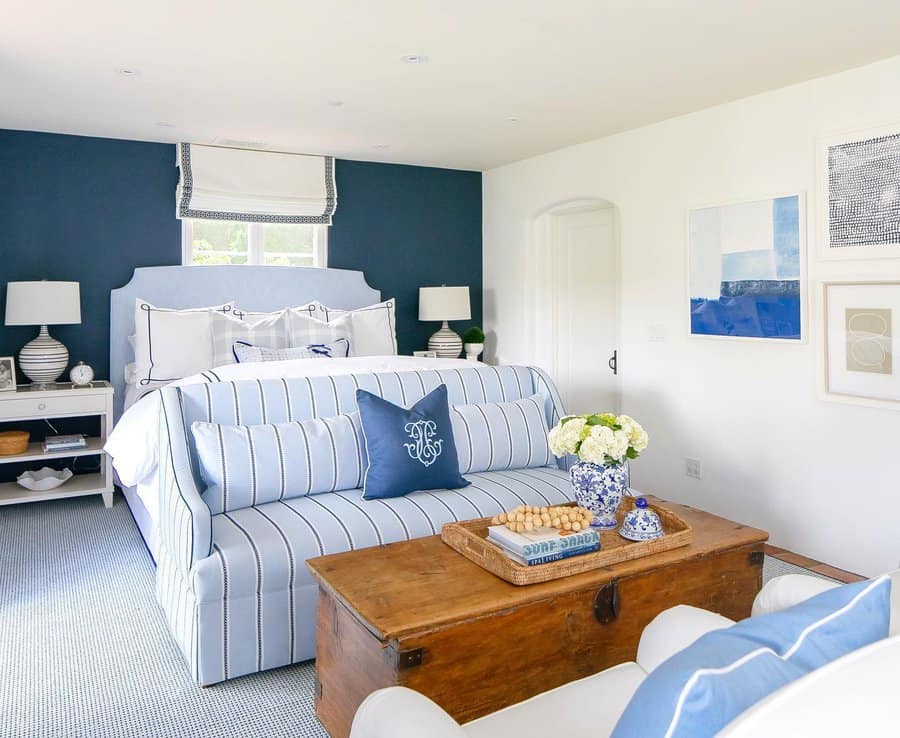 Coastal bedroom with navy accent wall and striped sofa