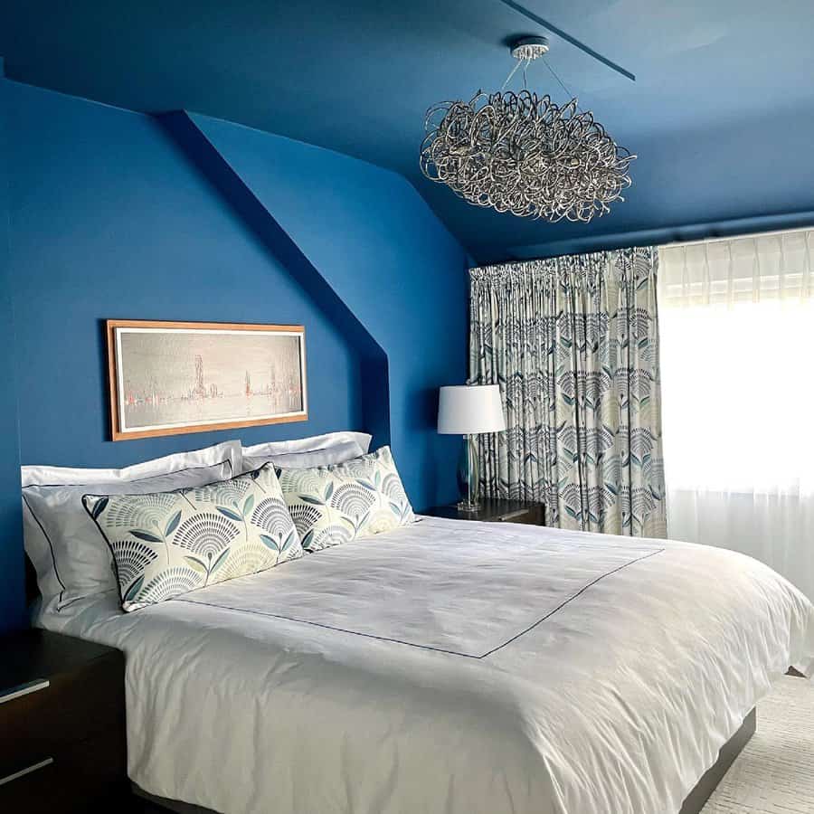 Modern bedroom with vibrant blue walls and artistic chandelier