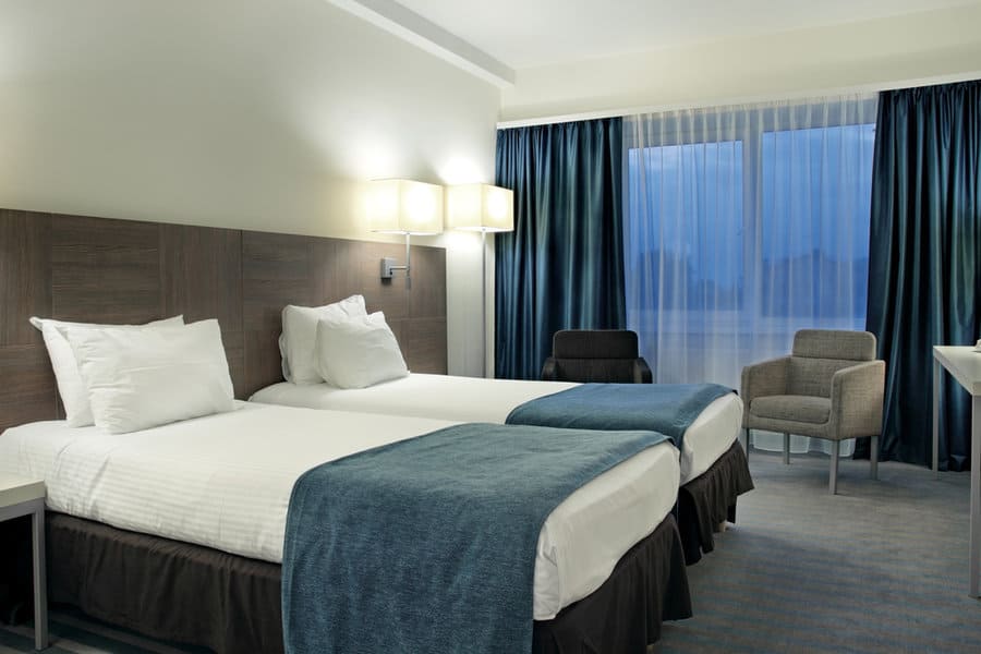 Hotel room with dark blue curtains and twin beds