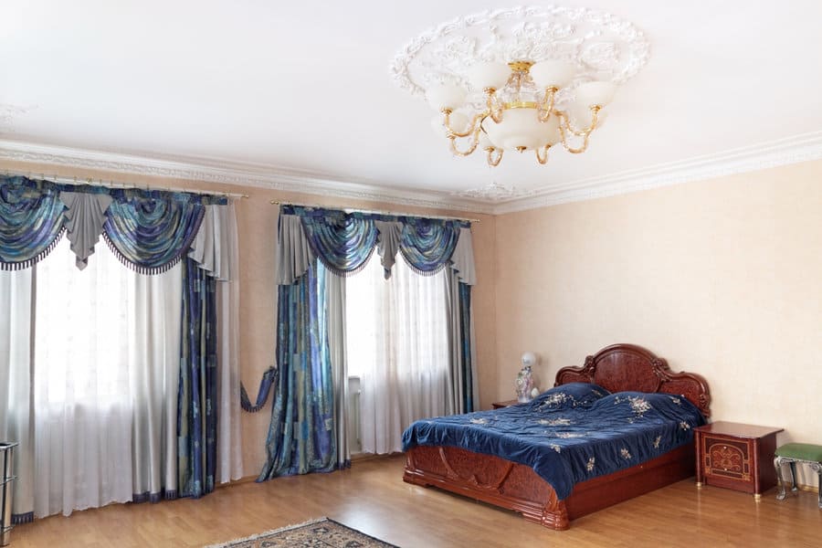 Classic bedroom with ornate blue drapes and chandelier