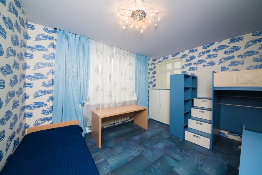 Child’s room with blue car themed wallpaper and curtains