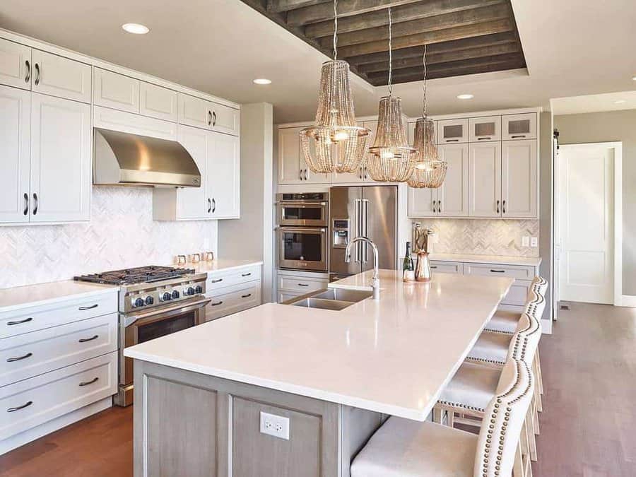 Elegant kitchen with chandeliers and white cabinetry