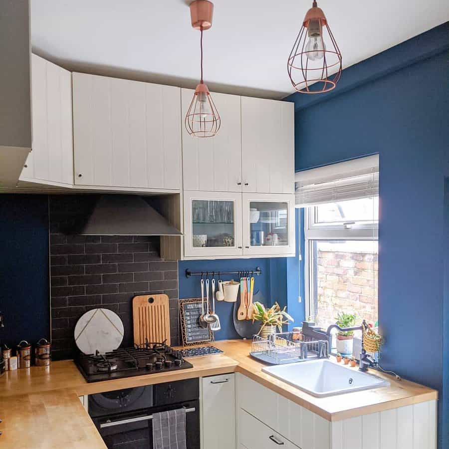 Stylish kitchen with navy blue walls and copper pendants