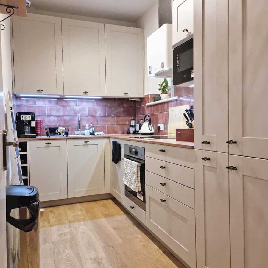 Small kitchen with beige cabinets and red tile backsplash