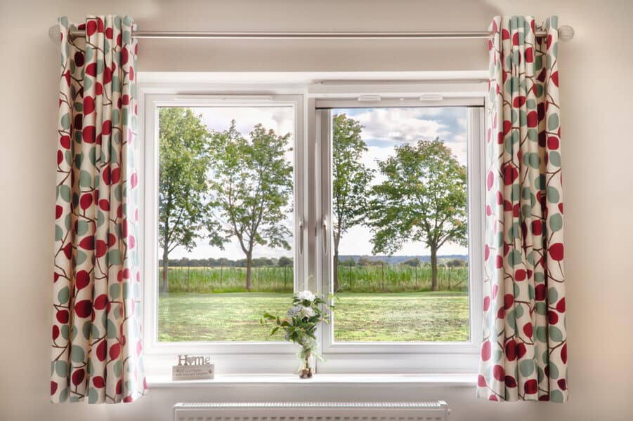 Bright window with patterned curtains and countryside view