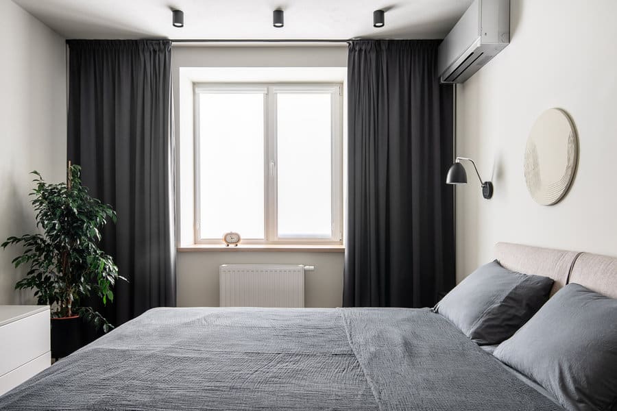 Minimalist bedroom with black curtains and wall sconce