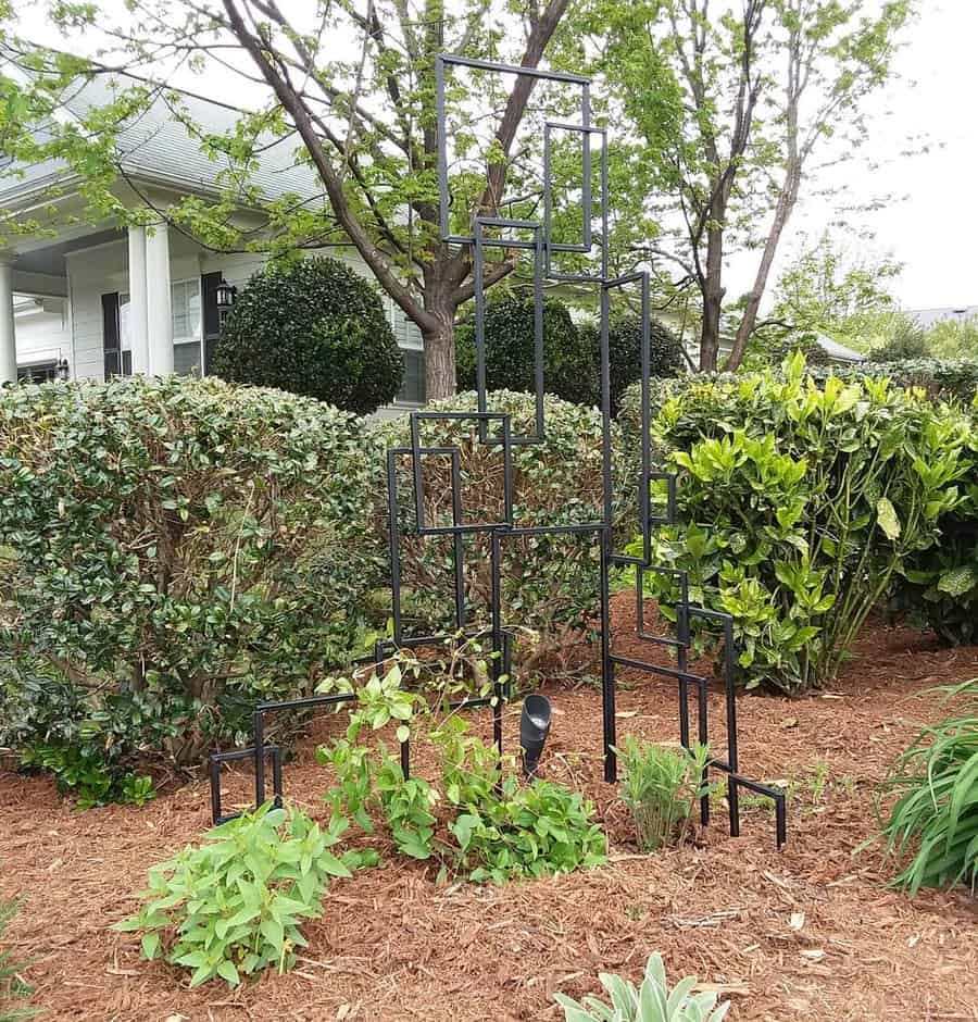 Metal garden trellis among shrubs in front yard