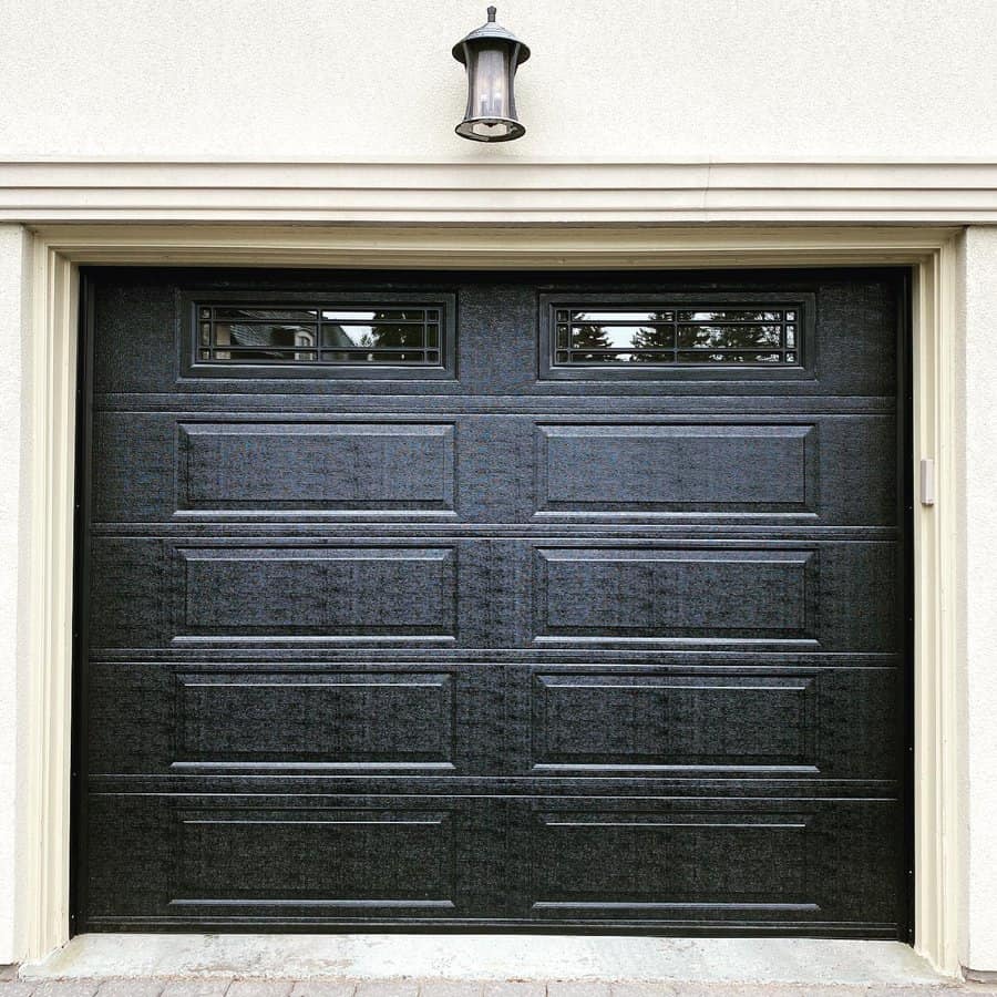 Modern black garage door with window panels and exterior light