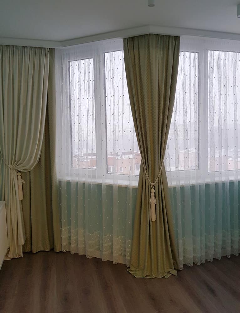 Curved bay window with elegant green drapes and sheers