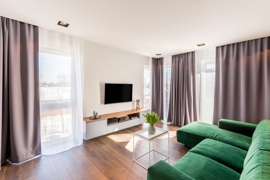 Modern living room with green sofa and grey curtains