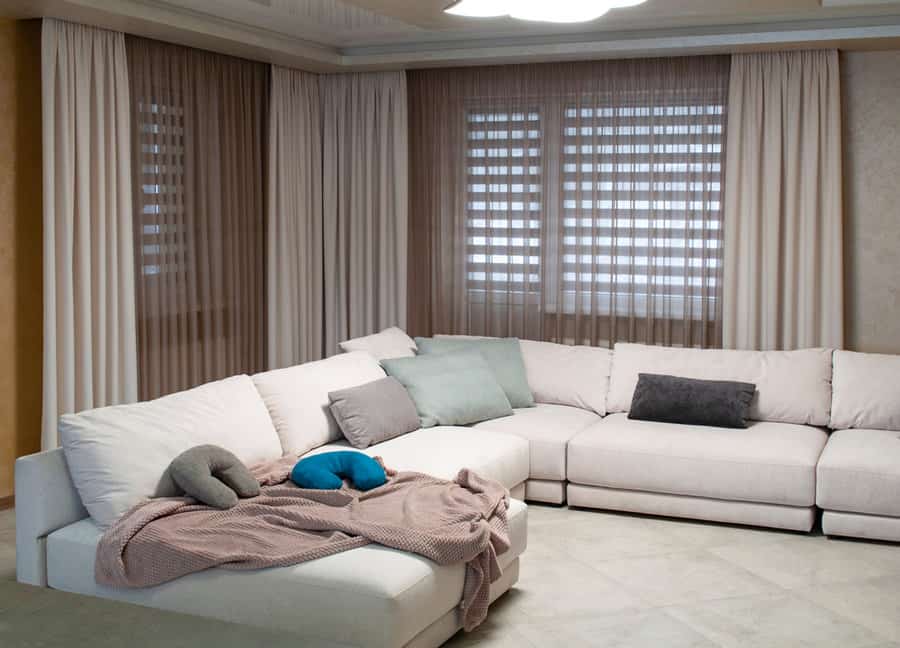 Cozy corner sofa with beige drapes and blinds