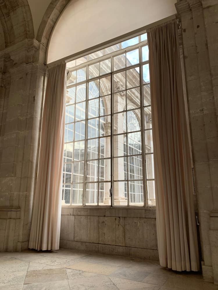 Grand arched window with tall beige drapes in stone room