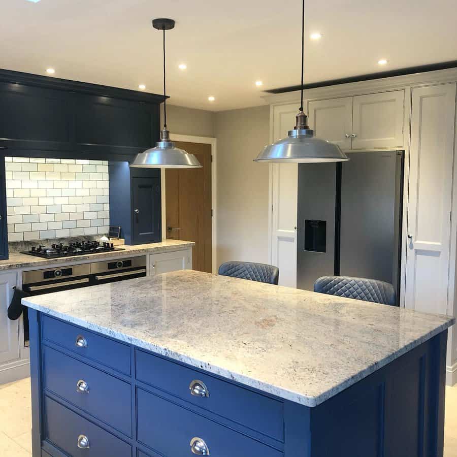 Stylish kitchen with navy island and silver pendants