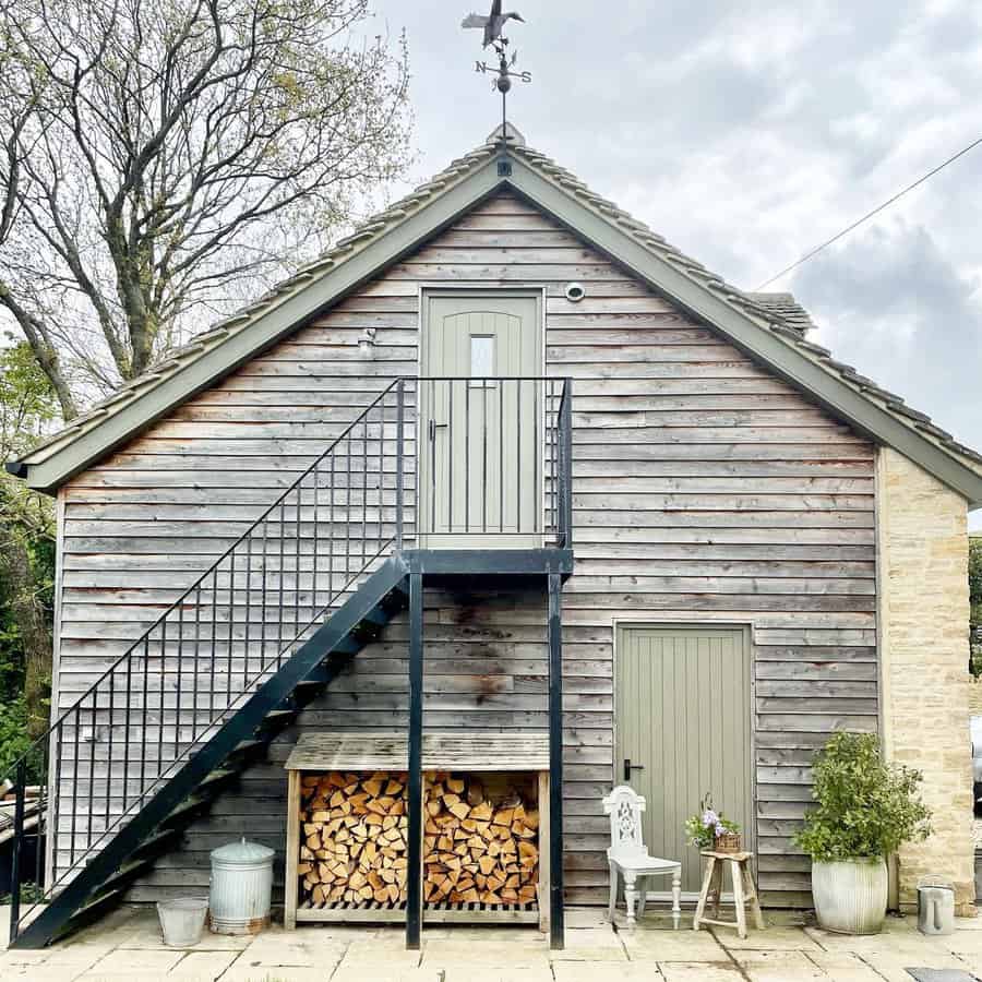 Rustic two story garage with external  staircase and woodpile