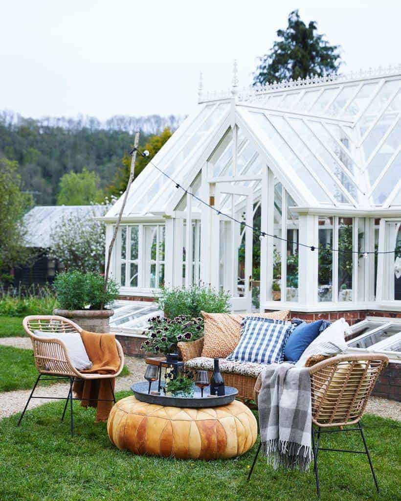 Cozy seating area outside a classic white greenhouse