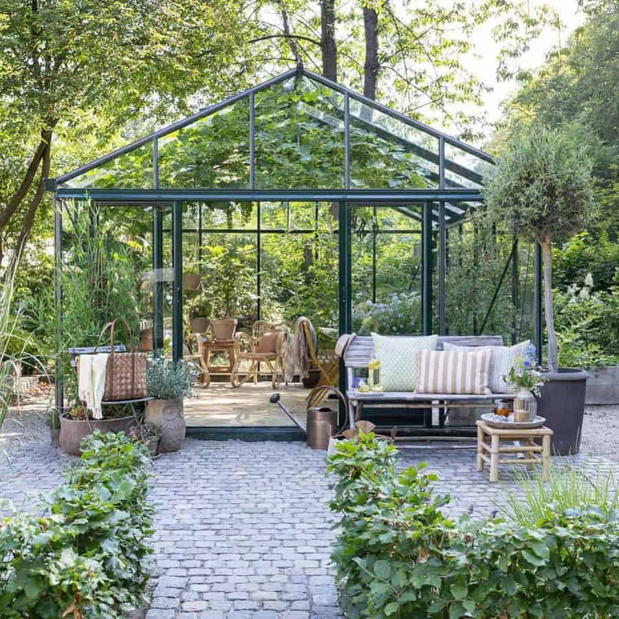 Outdoor greenhouse with lounge area and lush garden