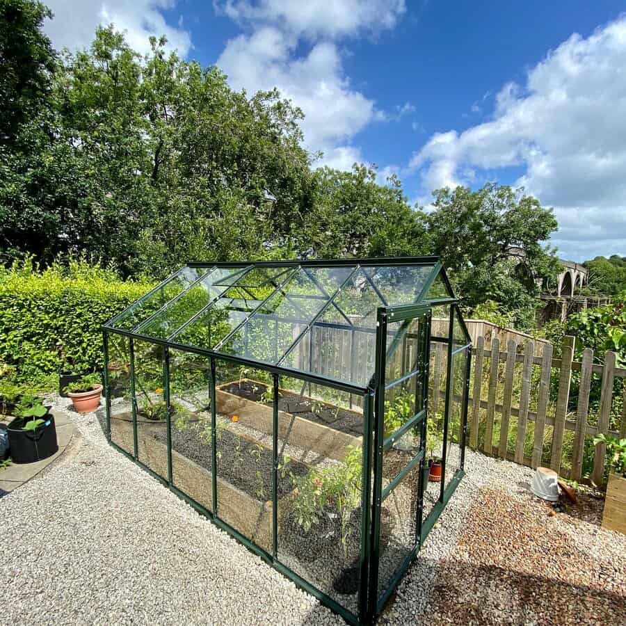 Compact greenhouse in a garden with clear skies above