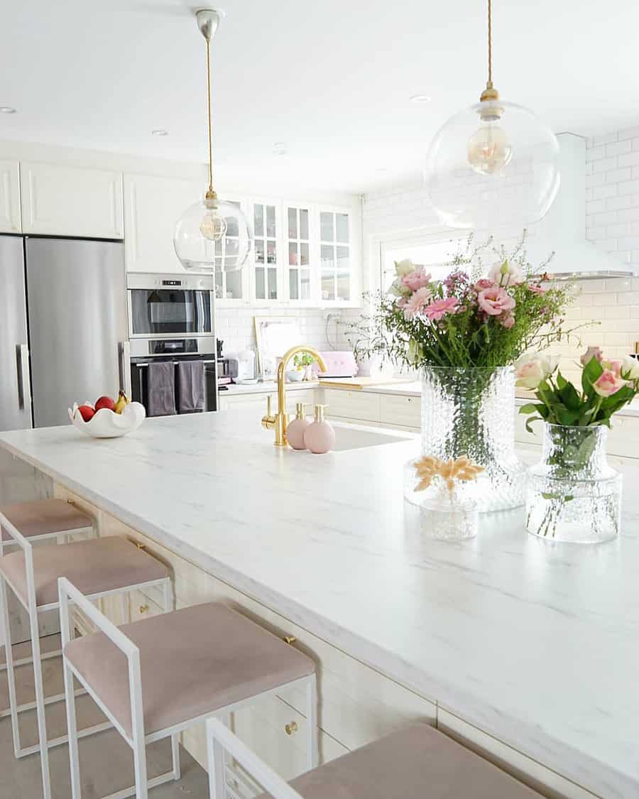 Bright white kitchen with elegant glass pendants and floral decor