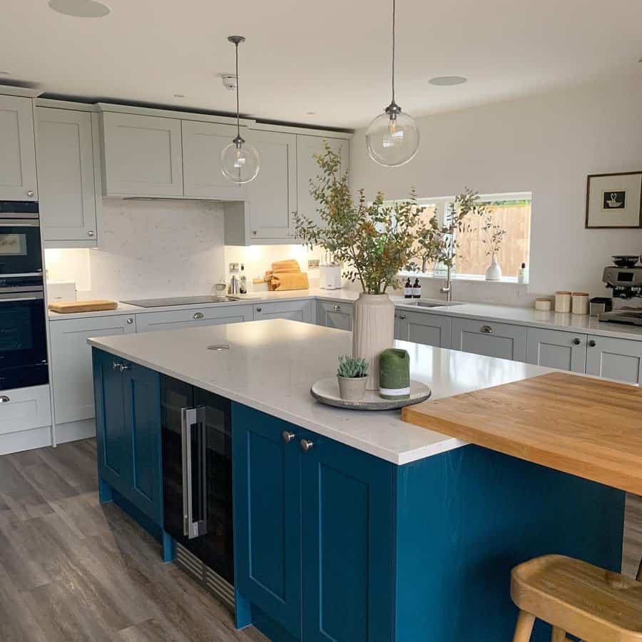 Inviting kitchen with clear pendants and blue island