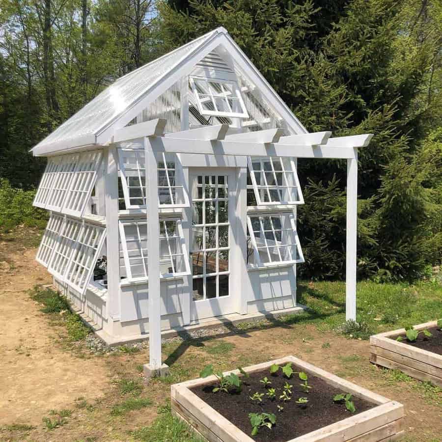 White greenhouse made with repurposed windows in a garden setting