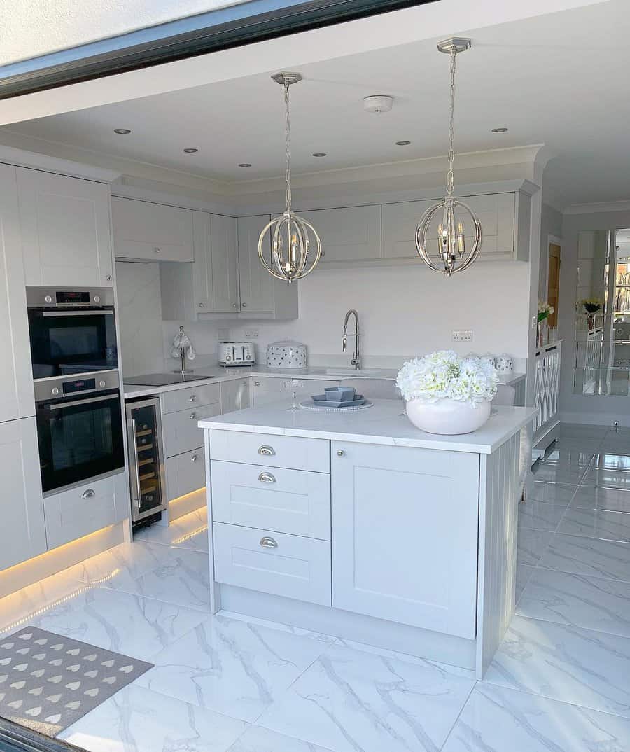 Chic white kitchen with elegant orb chandeliers and marble floor