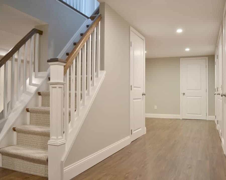 Staircase with white railing featuring white doors and wood flooring