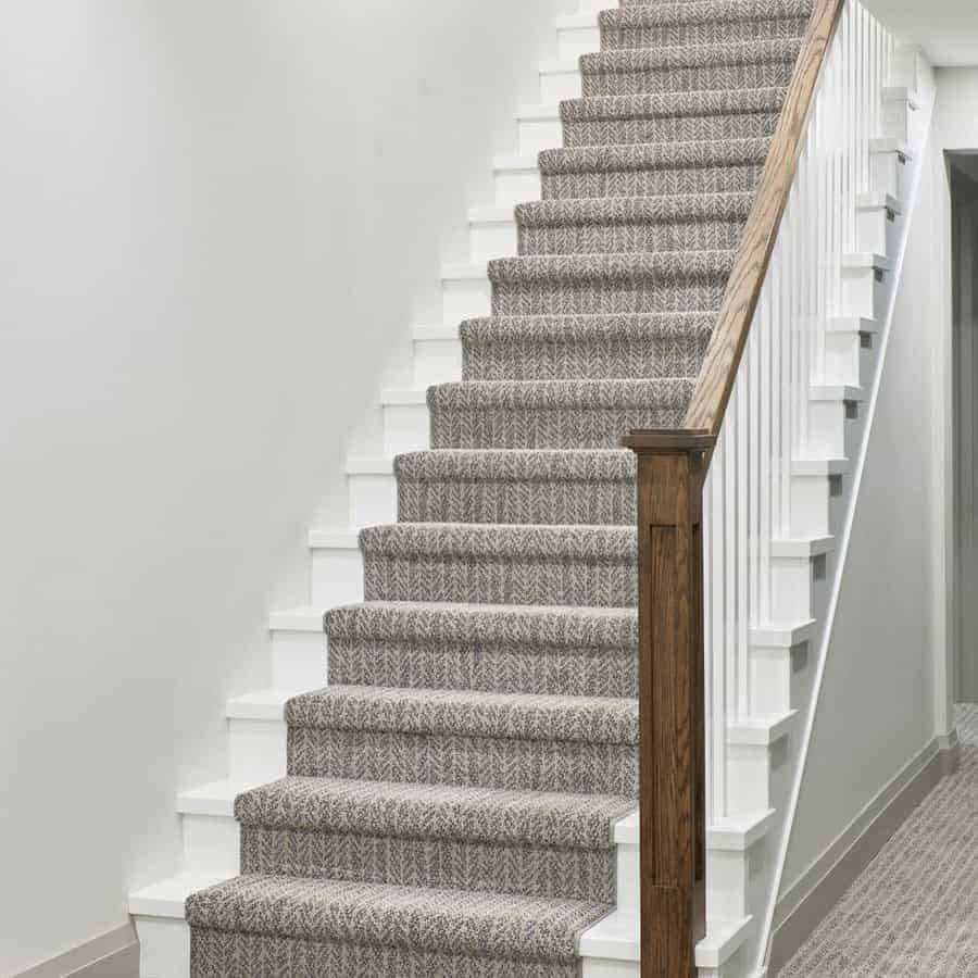 Staircase with a wooden railing and a carpeted tread