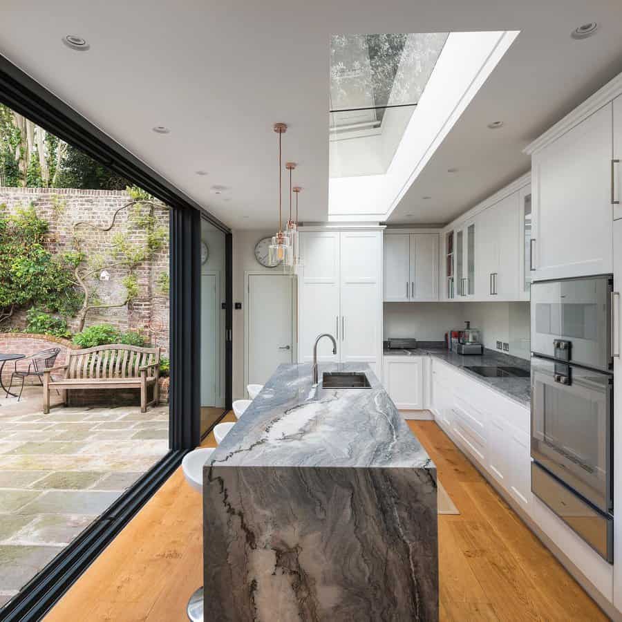 Skylit kitchen with marble island leading to garden